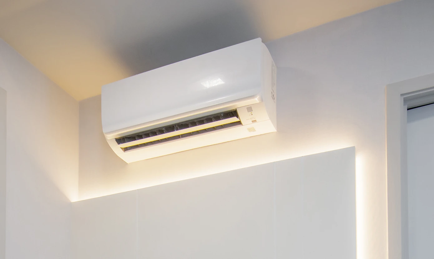 Homme en polo rouge utilisant un système de nettoyage vapeur sur une surface vitrée dans un environnement professionnel avec véhicules en arrière-plan