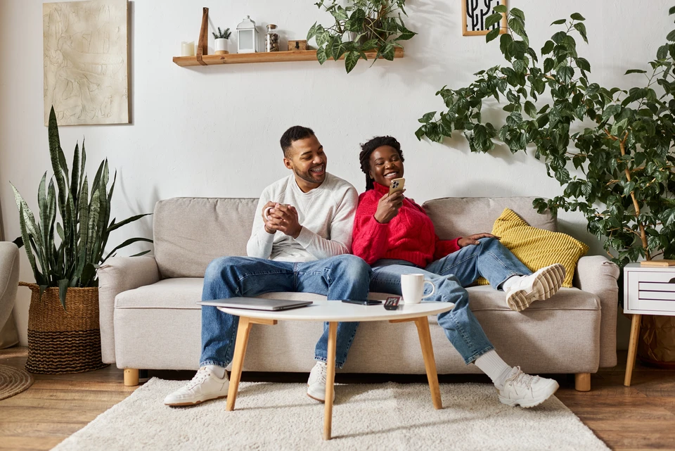 Personne en chaussettes rouges à motifs se relaxant près d'une fenêtre avec vue montagnarde enneigée, tasse de café posée sur rebord